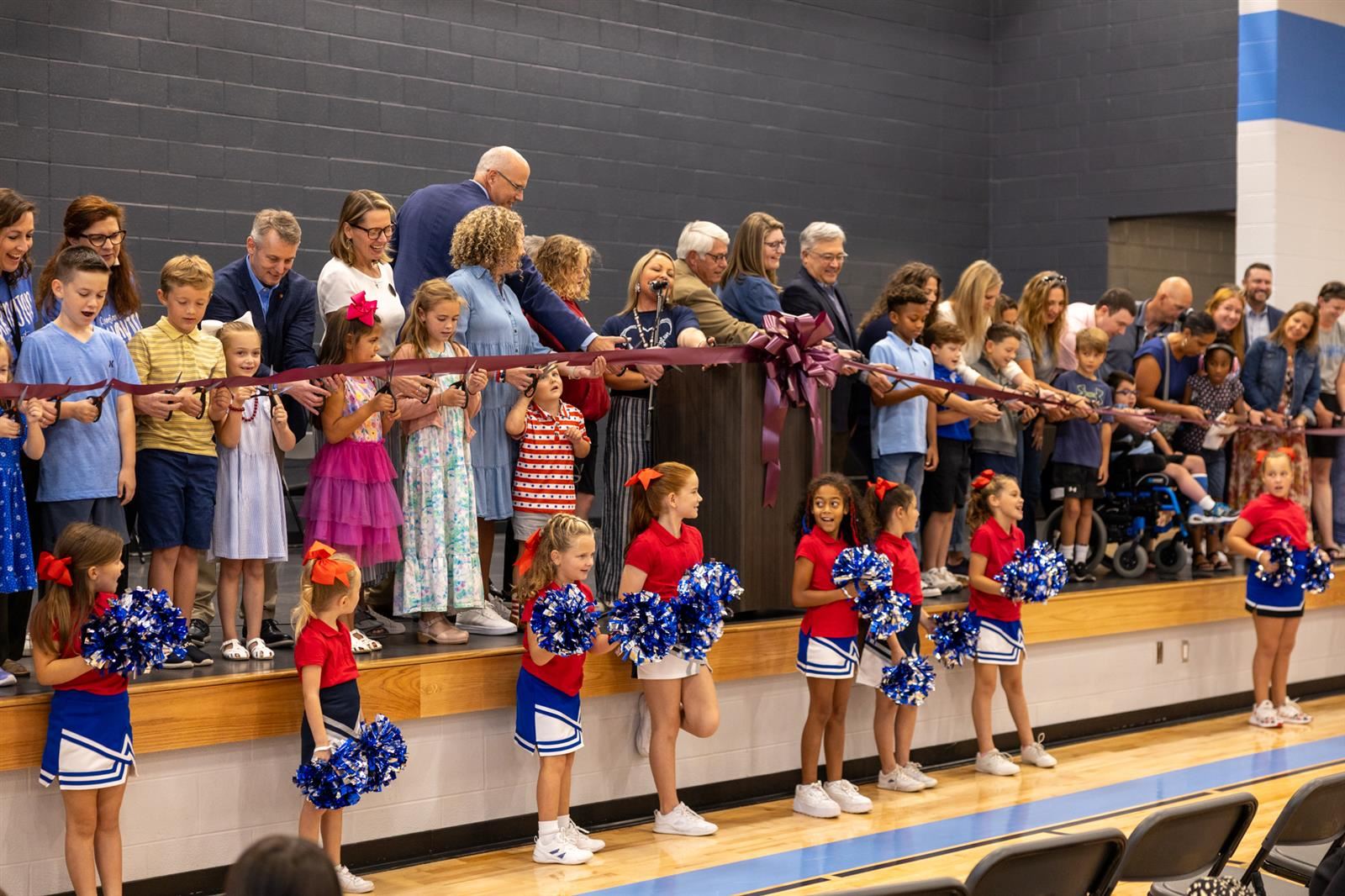 people on a stage cutting a ribbon